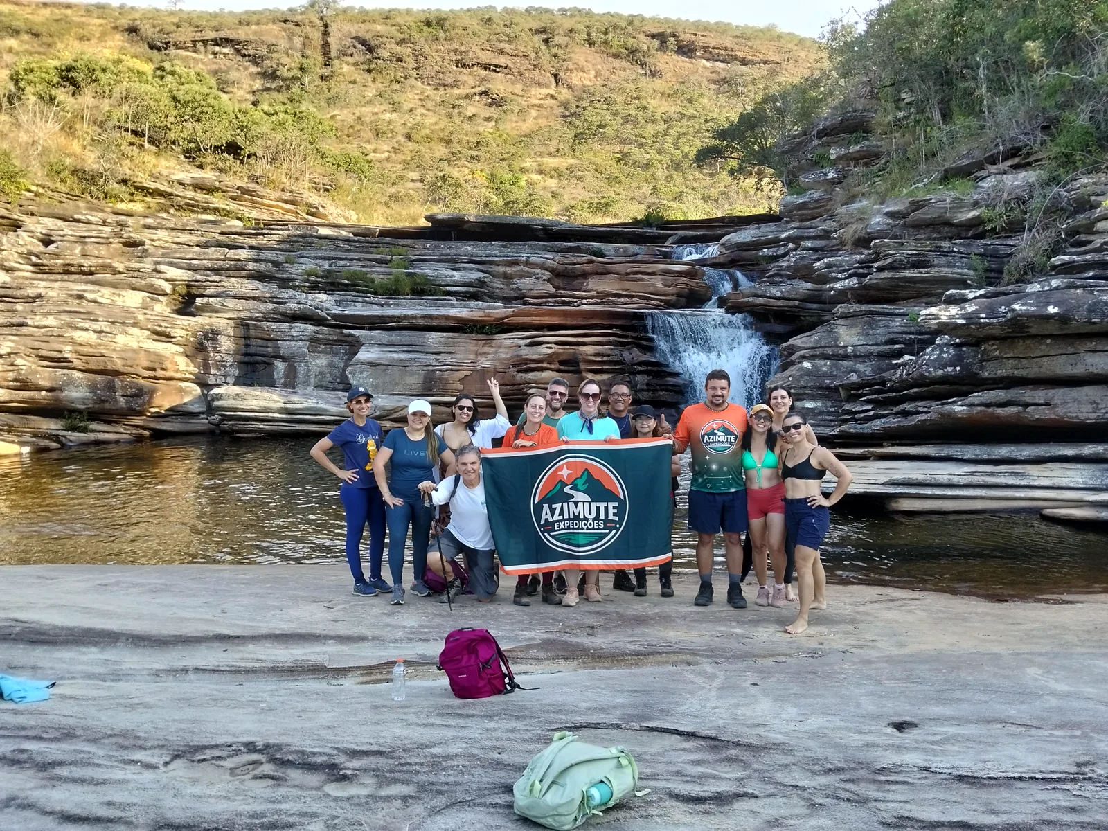 Grupo fechado da Azimute reunido diante de uma cachoeira